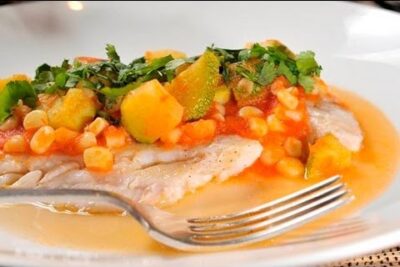 Filete de pescado con salsa de tomate, maíz y calabacín adornado con hierbas 3ng88kqPtvI