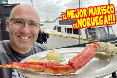Persona sonriente con una gran pierna de cangrejo real y salsa frente a un muelle 7pIYYjJcl98