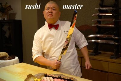 Maestro de sushi serio con cuchillo largo y bandeja de nigiris y makis IGCIX3kLzLw