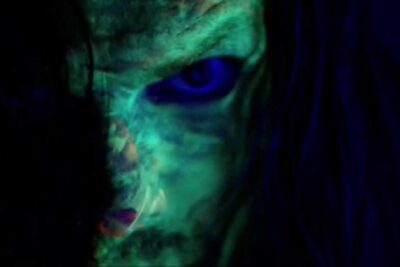 Primer plano de un rostro maquillado con pintura fluorescente en tonos verdes y azules IIhRwOeIHjo.