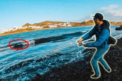 Pescador en la orilla lanzando la caña hacia una ola marcada en la costa PpT SpwU5oY