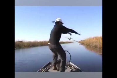 Pescador en bote lanzando caña en canal con juncos QqGm5reO bc