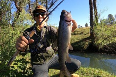 Pescador sosteniendo una trucha grande junto a un arroyo, SyZH9T5wTVw.