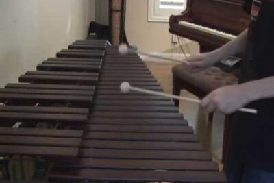 Persona tocando una marimba con mazas sobre teclas de madera Zcu8TH9UyPg