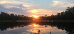 Kayak naranja en un lago tranquilo al amanecer con dos cañas, almacenamiento optimo kayak pesca consejos clave para organizar el equipo de pesca.