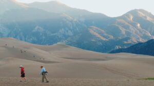 Personas caminando por dunas con montañas al fondo, imagen evocadora para guías sobre como evitar mosca hunda agua salada consejos trucos