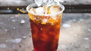 Vaso plástico con bebida oscura y cubitos de hielo salpicando, consejos maximizar agujeros pesca hielo