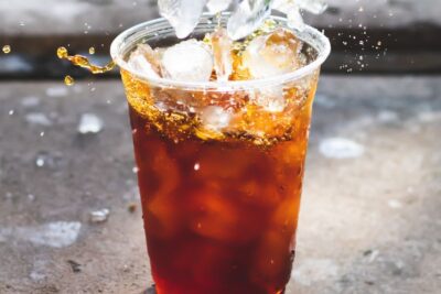 Vaso plástico con bebida oscura y cubitos de hielo salpicando, consejos maximizar agujeros pesca hielo