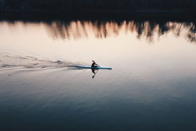 Remero solitario en kayak sobre agua tranquila al atardecer donde encontrar resenas kayaks pesca