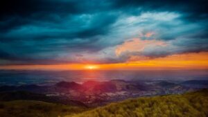 Atardecer sobre colinas con cielo dramático y praderas en primer plano, ideal para equipo esencial competir pesca hielo guia completa