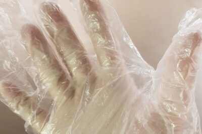 Guantes pesca agua salada mosca recomendables mostrados como guante desechable transparente en una mano