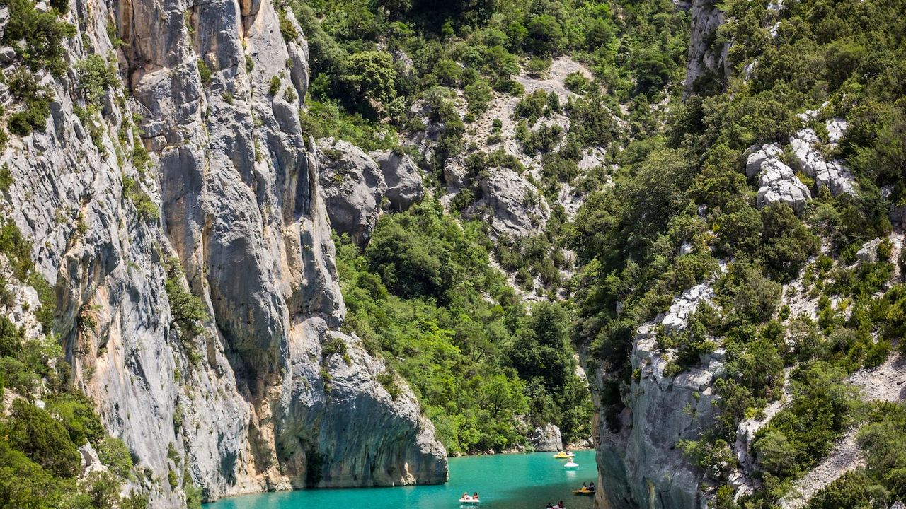 Kayaks en aguas turquesas entre acantilados y vegetación, kayak pesca mejor aventuras acuaticas