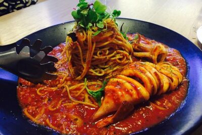 Plato de spaghetti con salsa de tomate y calamar entero en rodajas que ilustra la mejor manera de cocinar pescado entero pesca hielo