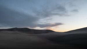 Dunas ondulantes al atardecer bajo un cielo amplio y nublado, composición minimalista ideal para las mejores moscas pesca mosca agua salada