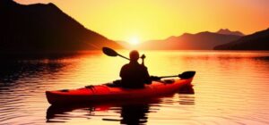Kayak rojo en silueta remando al atardecer sobre un lago sereno, ilustrando los mejores destinos para pescar en kayak guia completa