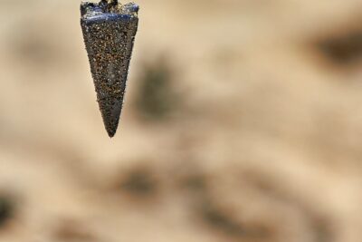 Plomada cónica cubierta de arena colgando en primer plano mejor anzuelo pesca hielo guia consejos