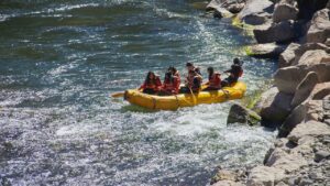 Grupo en una balsa amarilla remando en aguas rápidas que inspira la mejor tecnica remar kayak pesca.