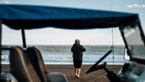 Pescador en la orilla con caña y embarcación, imagen ideal para mejores tecnicas pescar truchas aguas profundas