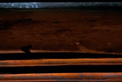 Detalle de tuberías metálicas oxidadas apiladas en planos horizontales con contraste de sombras y luces anaranjadas, pesca con mosca en agua salada linea flotacion vs hundimiento