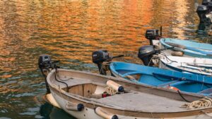 Botes de pesca pequeños amarrados con motores en agua que refleja tonos anaranjados pesca ilegal paises afectados combatirlo