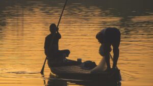 Pescadores en lancha al atardecer manejando redes y remos, pesca mosca agua salada caribe especies disponibles
