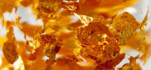 Macro de láminas doradas flotando en líquido con brillo metálico, pescar dorados consejos trucos mejor hora amantes pesca