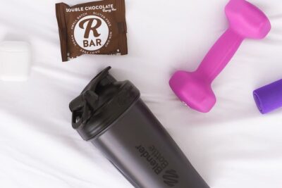 Accesorios de entrenamiento sobre fondo blanco con mancuernas, shaker y barrita energético peso seguro pescar hielo limite consejos