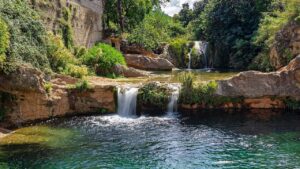 Cascadas y poza en río rocoso con vegetación, recordando precauciones pescar areas corrientes fuertes