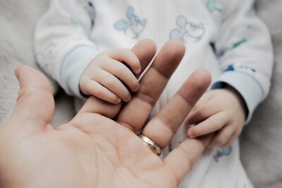 Mano de adulto con anillo sosteniendo la pequeña mano de un bebé, que cana pescar mejor pescar kayak