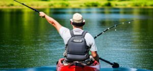 Pescador en kayak rojo con chaleco y caña en un lago tranquilo mostrando recomendaciones consejos accesorios pesca kayak mosca