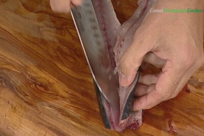 Manos fileteando un pescado con un cuchillo sobre una tabla de madera wnfpMipTUqE