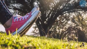Zapatillas rosas de lona en primer plano sobre césped al atardecer, zapatos pesca hielo resistencia frio durabilidad